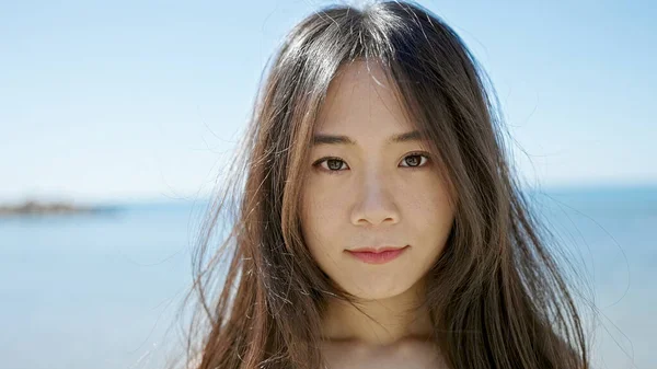 stock image Young chinese woman standing with serious expression at seaside