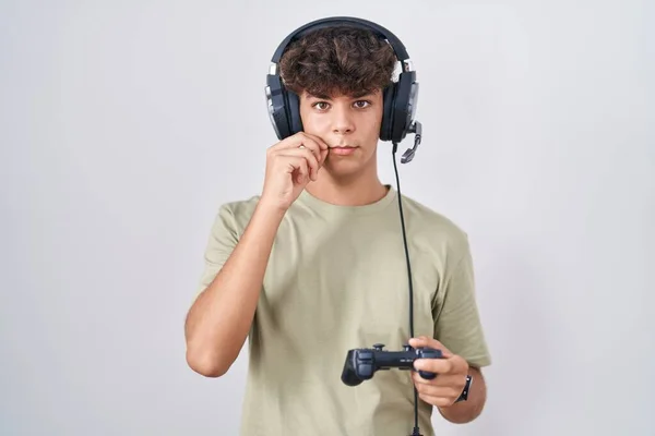Adolescente Hispânico Jogando Vídeo Game Segurando Boca Controlador Lábios Fechados — Fotografia de Stock