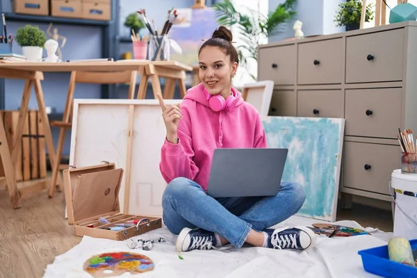 Young Hispanic Girl Using Laptop Painter Studio Smiling Happy Pointing — ストック写真