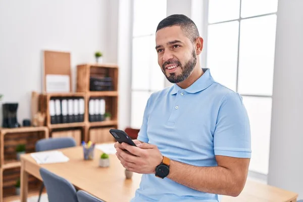 Young latin man business worker smiling confident using smartphone at office