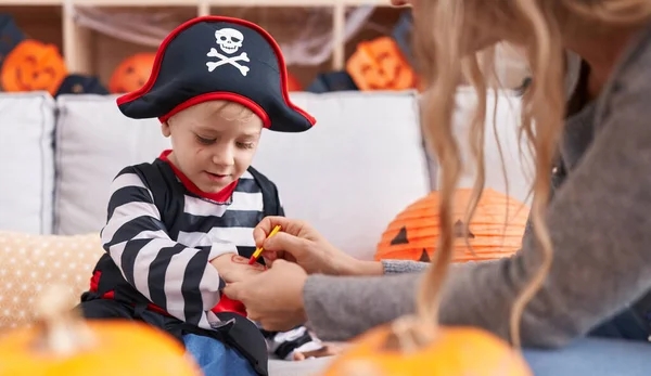 Adorable caucasian boy wearing pirate costume having draw on hand at home