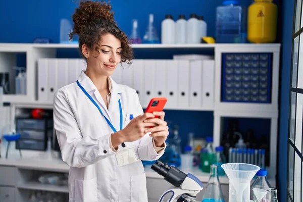 Молодая Латиноамериканка Ученый Улыбается Уверенно Используя Смартфон Лаборатории — стоковое фото