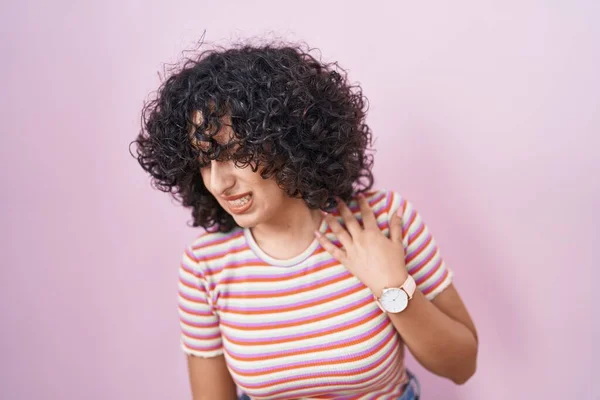 年轻的中东女人站在粉红的背脊上 用手触摸 肌肉疼痛 — 图库照片
