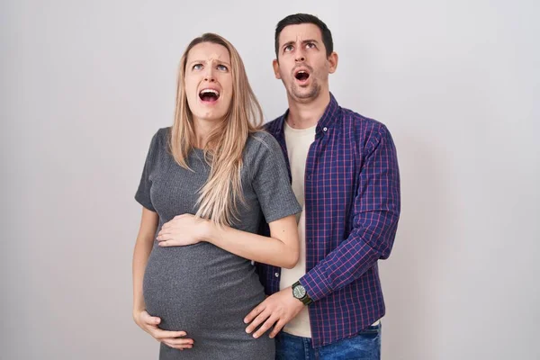 赤ん坊が白い背景の上に立っていることを期待している若いカップルは怒りで叫び 失望し 激怒し 怒って叫んで怒っている 怒りと攻撃的な考え方 — ストック写真