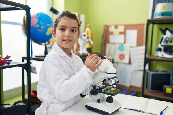 研究室の教室で顕微鏡を使用して自信を持って微笑む愛らしいパニック女子学生 — ストック写真