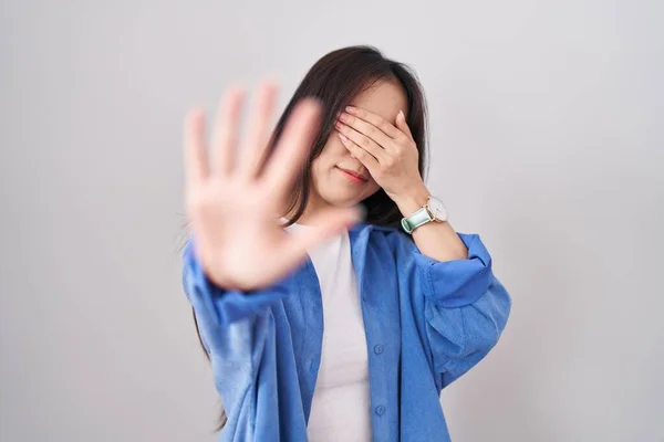 stock image Young chinese woman standing over white background covering eyes with hands and doing stop gesture with sad and fear expression. embarrassed and negative concept. 