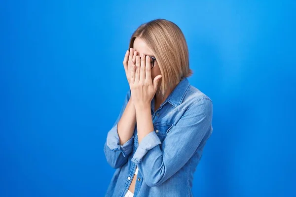 Mladá Běloška Stojí Nad Modrým Pozadím Smutným Výrazem Zakrývajícím Obličej — Stock fotografie