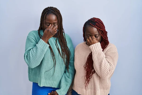 青い背景の上に立っている2人のアフリカ人女性は疲れ鼻をこすり 目は疲労と頭痛を感じる ストレスとフラストレーションの概念 — ストック写真