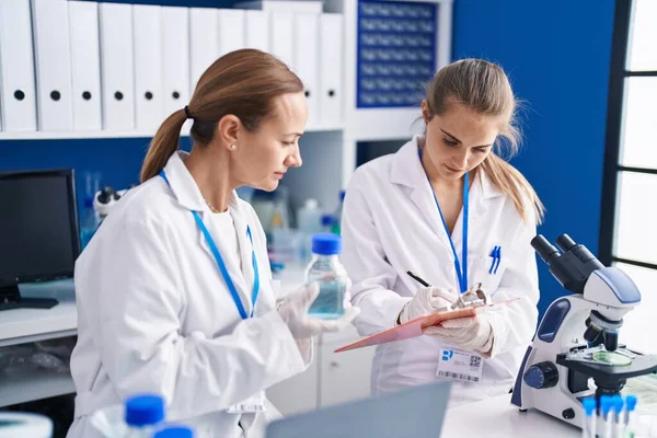 Две Женщины Учёные Пишут Измерении Жидкости Лаборатории — стоковое фото