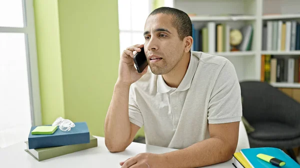 図書館大学で電話で話す若いヒスパニック系の学生 — ストック写真