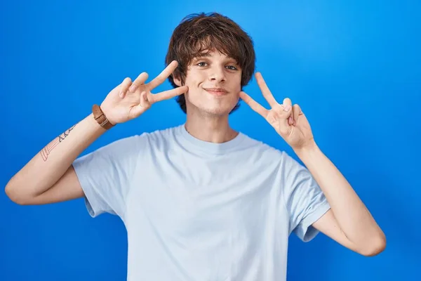 Іспанський Молодий Чоловік Стоїть Над Синім Фоном Зображає Мир Пальцями — стокове фото