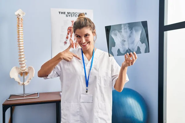 年轻女人拿着骨盆X线摄影指尖对着一个自己笑的快乐而自豪 — 图库照片