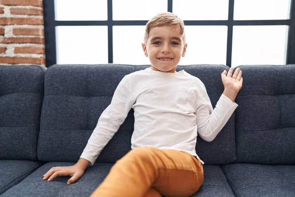 Adorable Hispanic Boy Saying Hello Hand Sitting Sofa Home — Stock fotografie