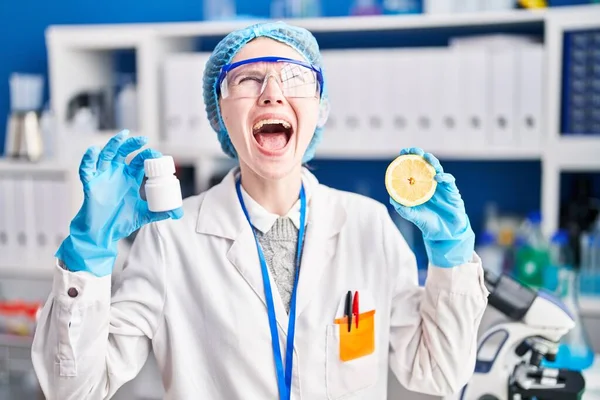 在科学家实验室工作的漂亮女人 手里拿着药丸和柠檬 怒气冲冲地尖叫着 怒气冲冲地大叫着 抬起头来 — 图库照片