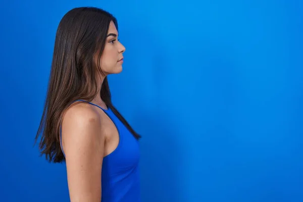 Mavi Arka Planda Dikilen Spanyol Kadın Yan Bakmak Rahat Poz — Stok fotoğraf