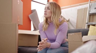 Yeni evinde ciddi bir ifadeyle kanepede oturan güzel İspanyol bir kadın.