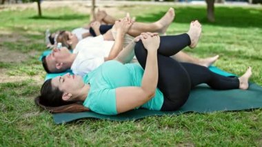 Bir grup insan parkta yoga eğitimi alıyor.