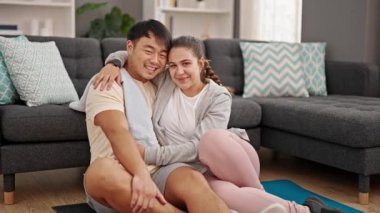 Erkek ve kadın çift evde oturmuş birbirlerine sarılıyorlar.