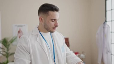 Klinikte steteskop takmış, ciddi bir ifadeyle duran genç İspanyol doktor.