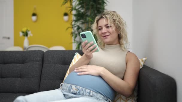 Молодая Беременная Женщина Помощью Смартфона Трогает Живот Дома — стоковое видео