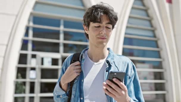 Młody Latynoski Student Uśmiecha Się Pewnie Używając Smartfona Uniwersytecie — Wideo stockowe