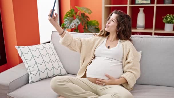 Genç Hamile Bir Kadın Akıllı Telefonuyla Fotoğraf Çekiyor Evdeki Kanepede — Stok video