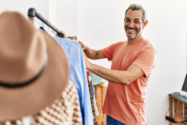 Orta yaşlı, gri saçlı, güler yüzlü, elbise mağazasında kendine güvenen bir müşteri.