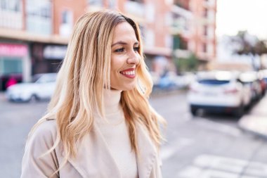 Young blonde woman smiling confident looking to the side at street