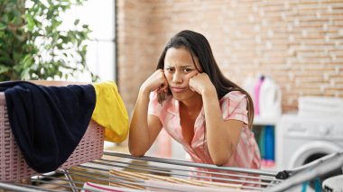 Çamaşır odasında çamaşır ipine yaslanan genç, güzel İspanyol kadın.