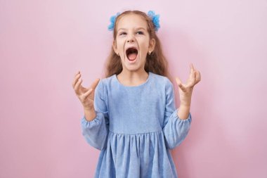 Pembe arka planda duran küçük kız çılgın ve kızgın bir şekilde bağırıyor ve agresif bir ifade ve kolla bağırıyor. hüsran kavramı. 