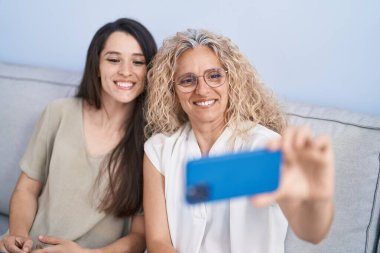 İki kadın anne ve kız evde akıllı telefondan selfie çekiyorlar.