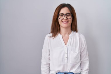 Yüzünde mutlu ve havalı bir gülümseme olan esmer bir kadın izole edilmiş beyaz arka planda duruyor. şanslı kişi. 