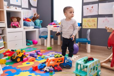 Anaokulunda duran sevimli İspanyol çocuk oyuncak arabasıyla oynuyor.