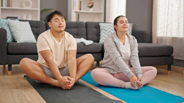 Erkek ve kadın çift evde yoga egzersizi yapıyor.