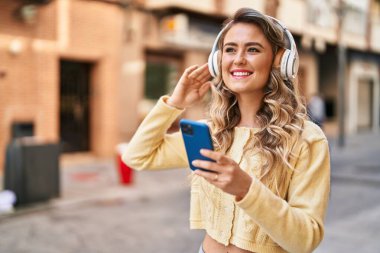 Sokakta müzik dinlerken kendinden emin gülümseyen genç bir kadın.