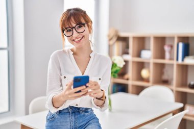 Evde akıllı telefon kullanan kendine güvenen genç bir kadın.