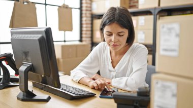 Genç, güzel İspanyol bir kadın. İş kadını. Ofiste çalışırken akıllı telefon kullanıyor.