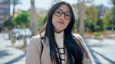 Parkta ciddi bir ifadeyle duran genç, güzel İspanyol kadın.