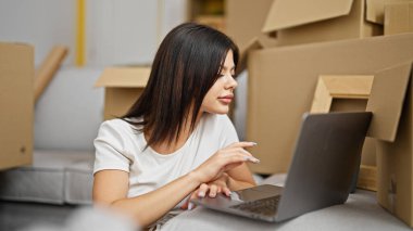 Young caucasian woman using laptop sitting on floor at new home