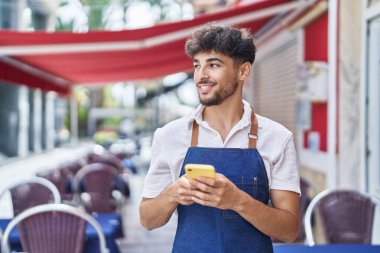 Young arab man waiter using smartphone working at restaurant