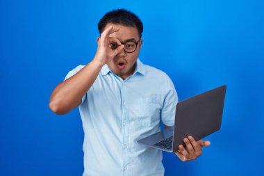 Bilgisayarı kullanan Çinli genç adam şaşırmış yüz ifadesiyle şaşırmış, parmaklarından bakan bir jest yapıyor. İnançsız ifade. 