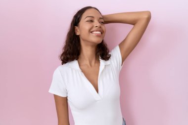 Günlük beyaz tişört giyen genç İspanyol kadın gülümsüyor. Saçlarına dokunuyor, el hareketi yapıyor, çekici ve modaya uygun poz veriyor. 