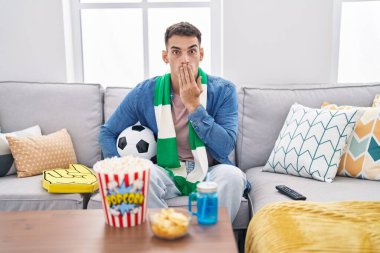 Top tutan yakışıklı İspanyol bir adam. Ağzı eliyle kaplayan top destekleyici bir takım. Şok olmuş ve hata yapmaktan korkuyor. şaşırmış ifade 