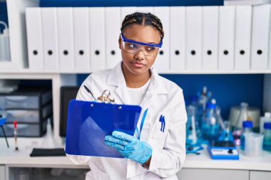 African american woman scientist writing report working at laboratory