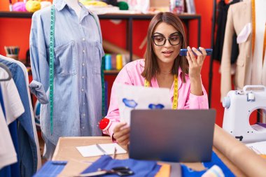 Young beautiful hispanic woman tailor smiling confident using laptop at atelier