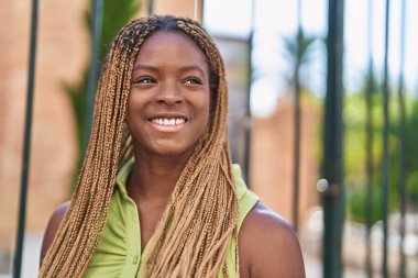 Afro-Amerikalı kadın gülümsüyor. Kendinden emin bir şekilde caddeye bakıyor.