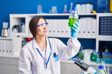 Genç ve güzel İspanyol bilim adamı. Laboratuvarda bir şişe su tutuyor.