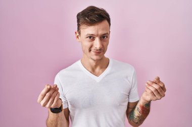 Pembe arka planda duran beyaz adam elleriyle para hareketi yapıyor, maaş istiyor, milyonerlik işi yapıyor. 