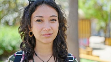 Parkta ciddi bir ifadeyle duran genç, güzel İspanyol kadın.