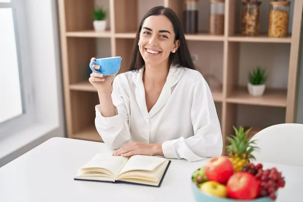 Young Hispanic Woman Reading Book Drinking Coffee Home — Fotografia de Stock
